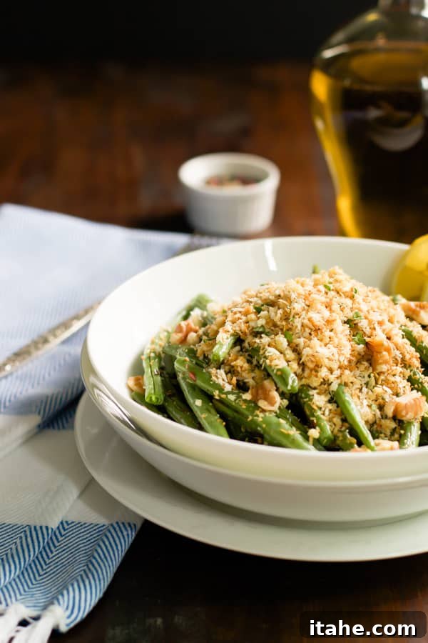 A side photo of a bowl of roasted green beans with garlic panko, highlighting the vibrant green and golden topping.