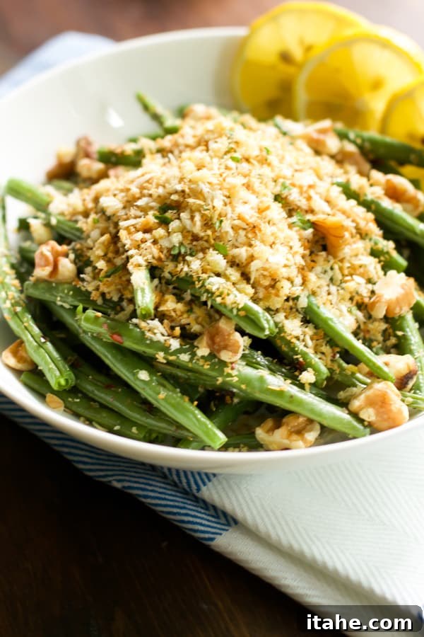 Close up image of a bowl of roasted green beans with garlic panko, showing the detail of the crispy crumbs.
