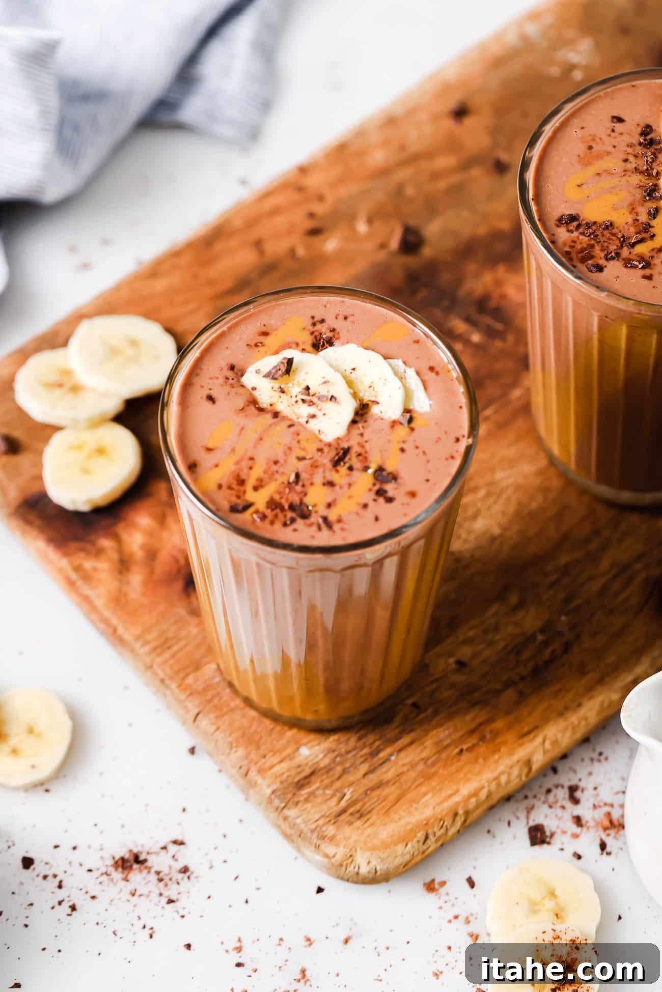 A peanut butter chocolate smoothie garnished with fresh banana slices on top.