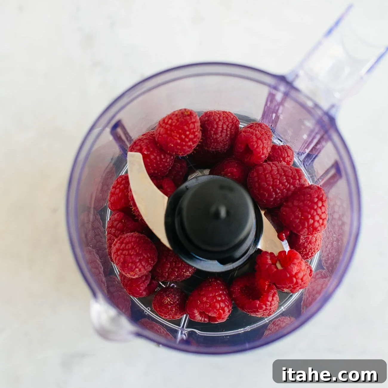 photo showing raspberries in a food processor being pureed.