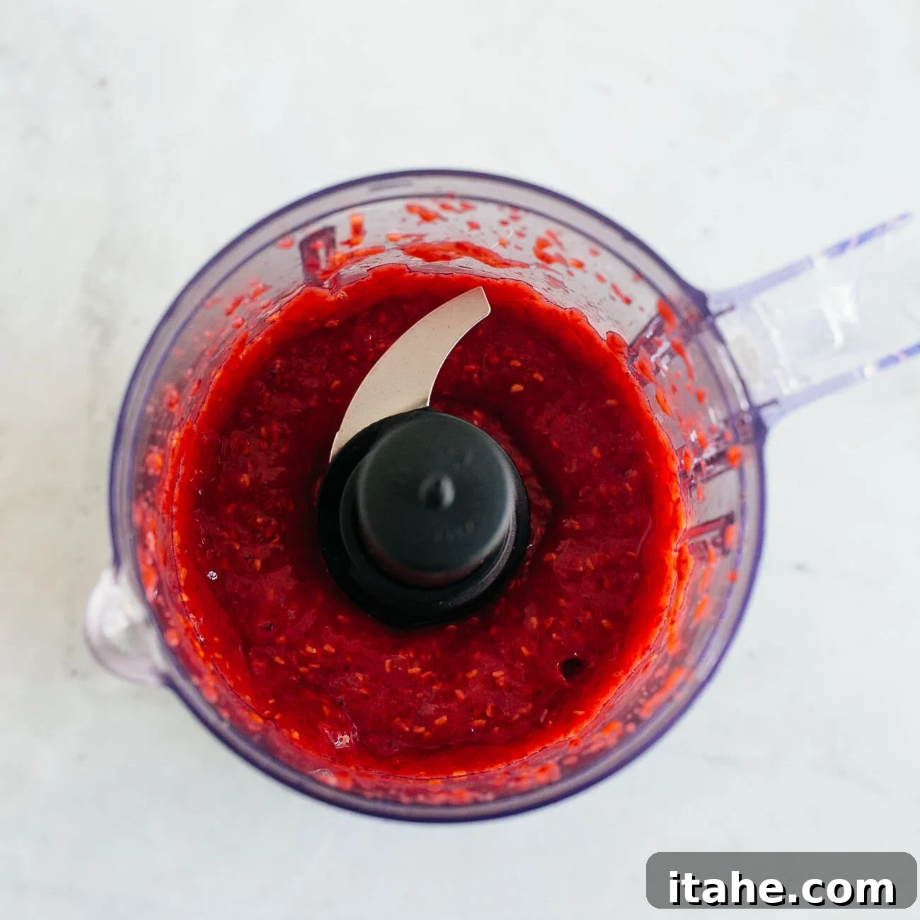 photo showing raspberries in a food processor being pureed.