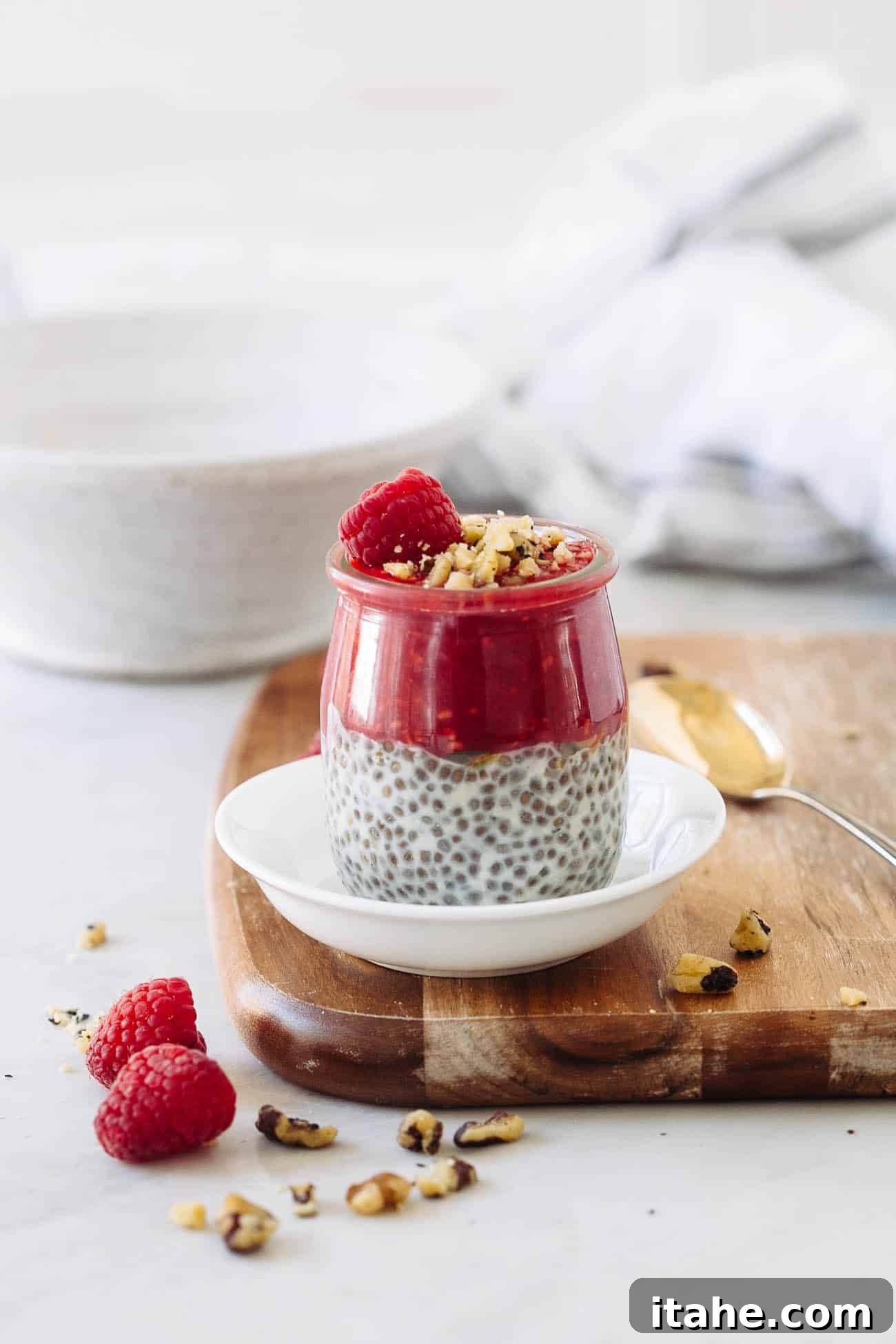 A jar of chia seed pudding with raspberry puree, raspberry, and pistachios on top.