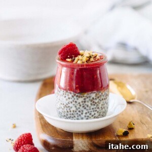 A jar of chia seed pudding with raspberry puree, raspberry, and pistachios on top.
