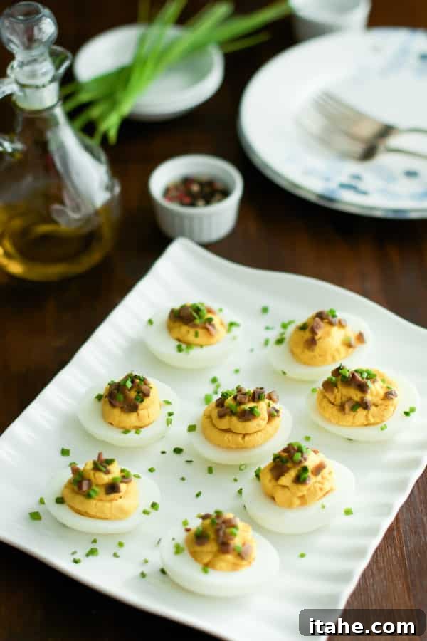Elegant Lentil Deviled Eggs A pristine white platter filled with an array of elegantly prepared lentil deviled eggs, ready to be served.