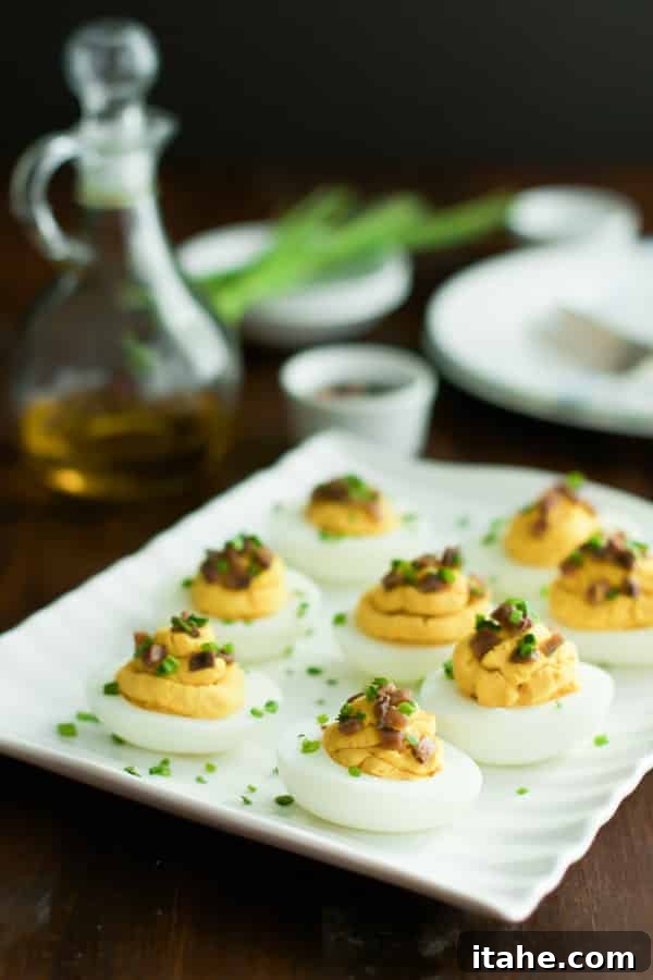 Lentil Deviled Eggs with Chives An angled close-up photo of a platter of lentil deviled eggs, generously sprinkled with fresh chives on top.