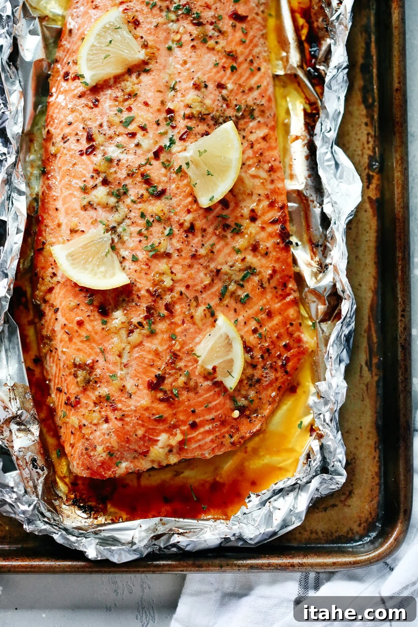 Mouthwatering Garlic Butter Salmon 2 Closeup vide of Baked Salmon in foil with lemon slices and garlic butter sauce.