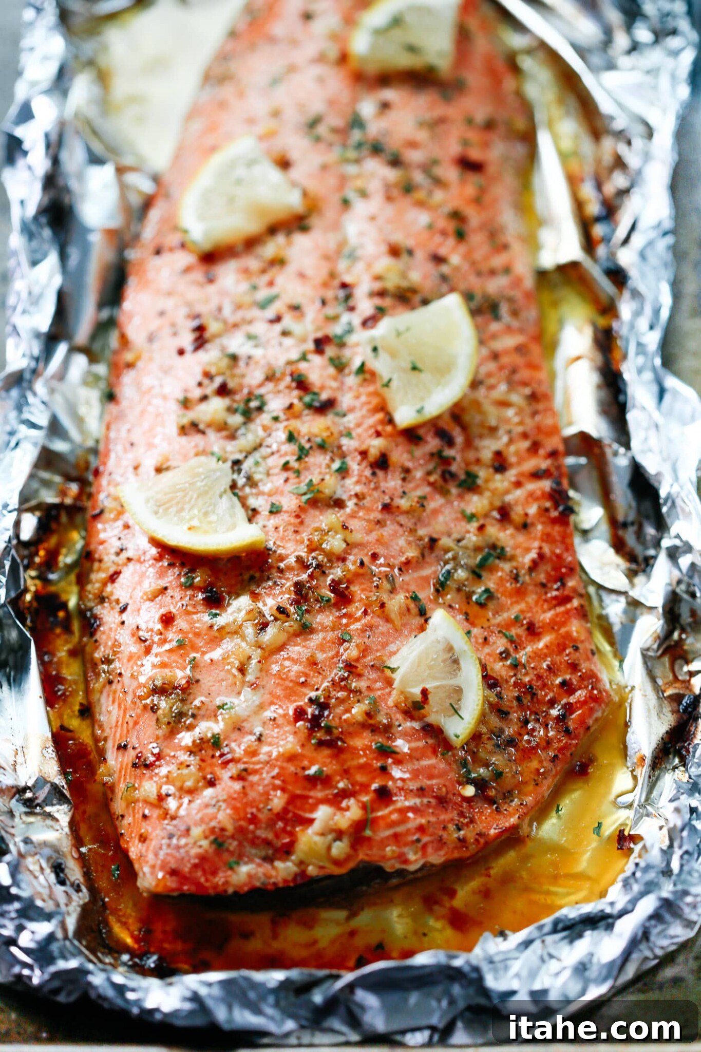Mouthwatering Garlic Butter Salmon 10 Closeup Baked fish with lemon slices and garlic butter sauce on the top.