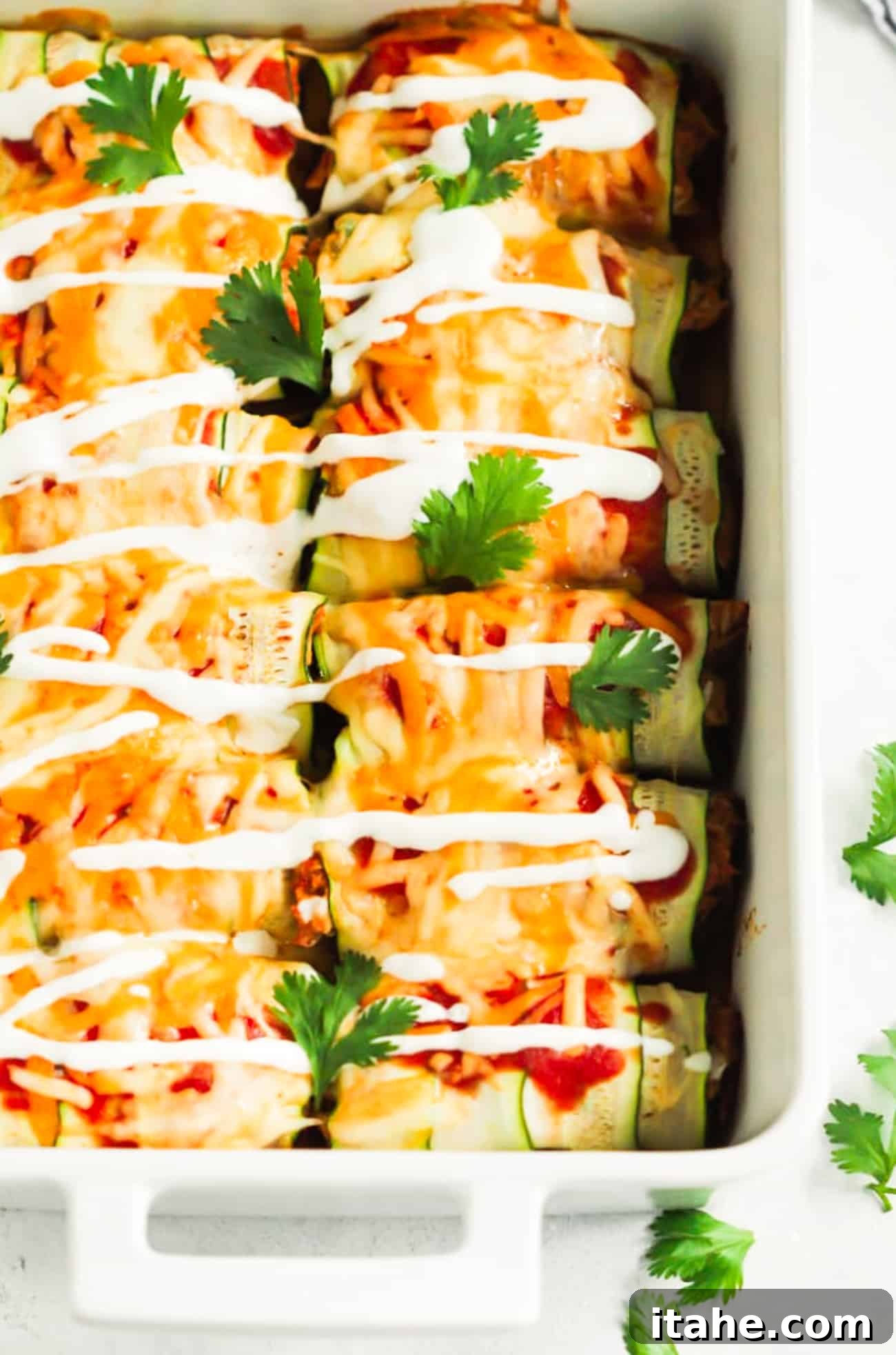 Delicious Keto Zucchini Chicken Enchiladas baked to golden perfection in a white casserole dish, garnished and ready to serve.