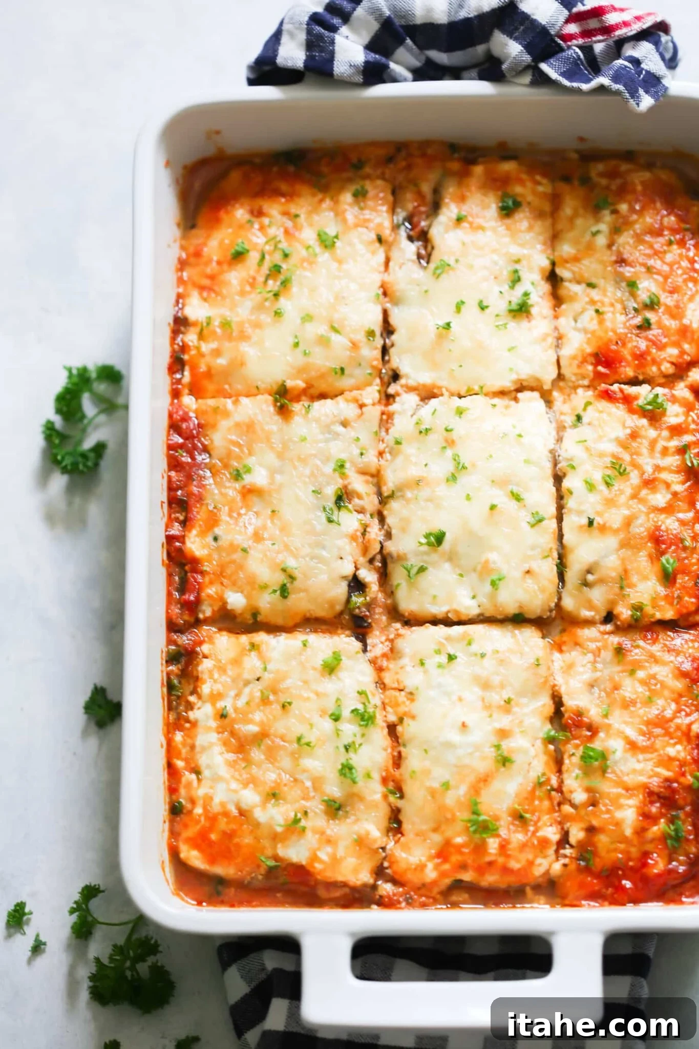 Delicious Low-Carb Eggplant Lasagna - A healthy, gluten-free alternative perfect for any meal. Low-carb eggplant lasagna in a large, white baking dish, freshly baked and garnished with herbs.