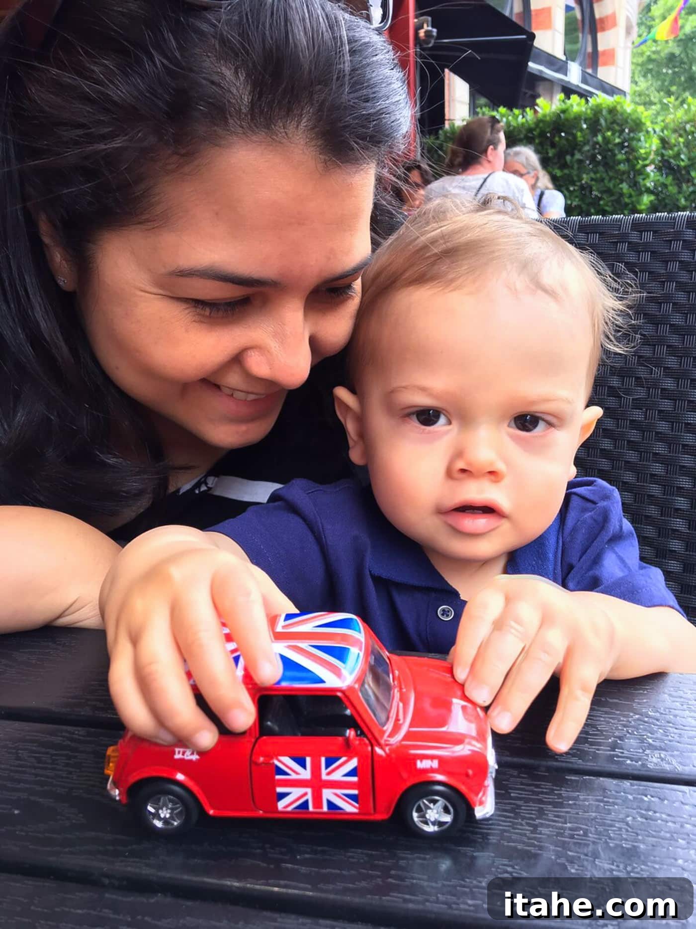 A mother and son playing with a toy Mini Cooper car, symbolizing London