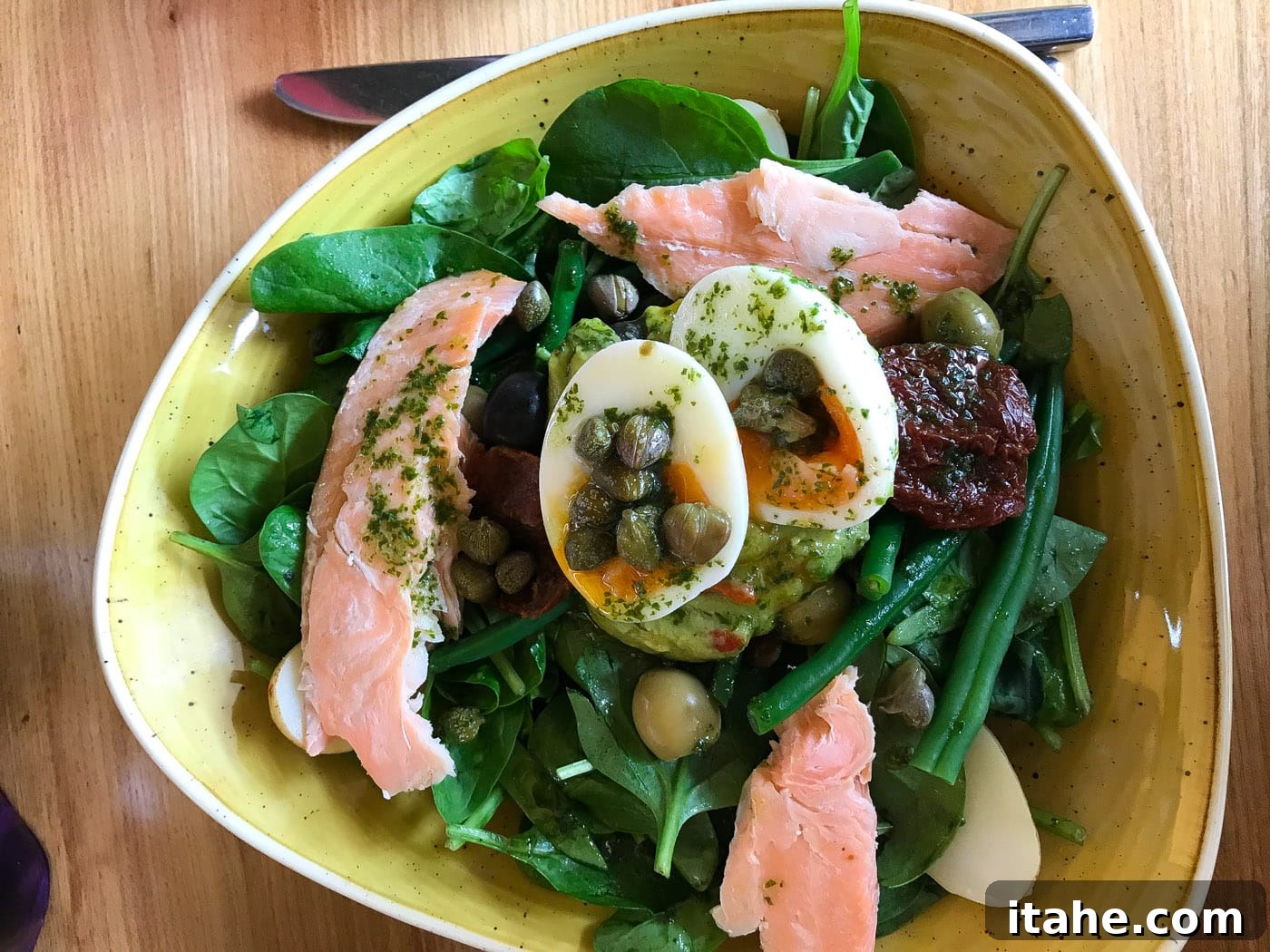 Overhead shot of a fresh salmon salad bowl on a rustic wooden table