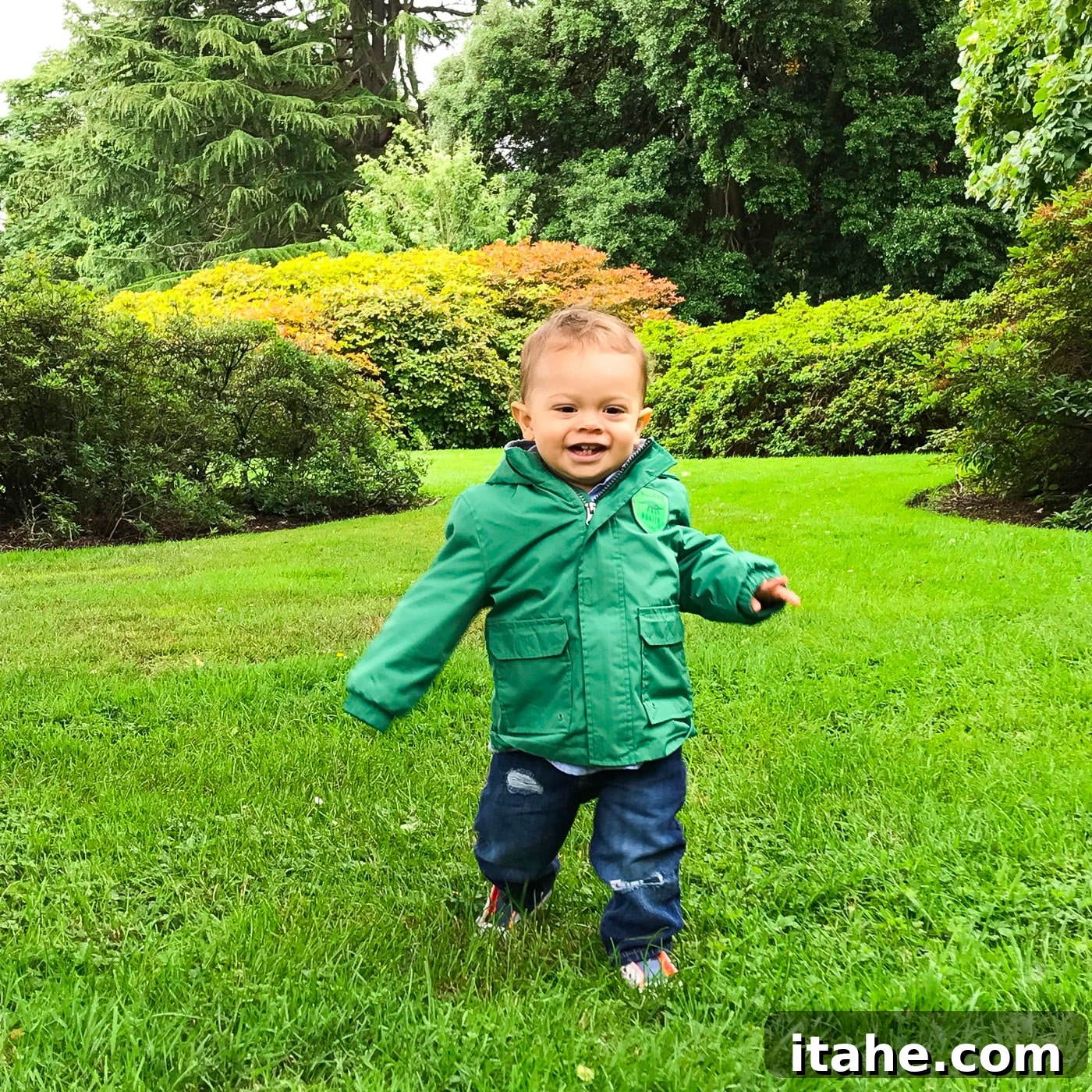 A joyful toddler running freely through a lush green park in Edinburgh