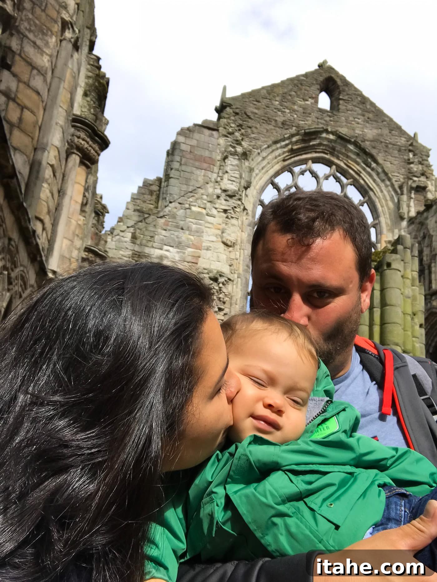 Parents showing affection by kissing their toddler on the head and cheek