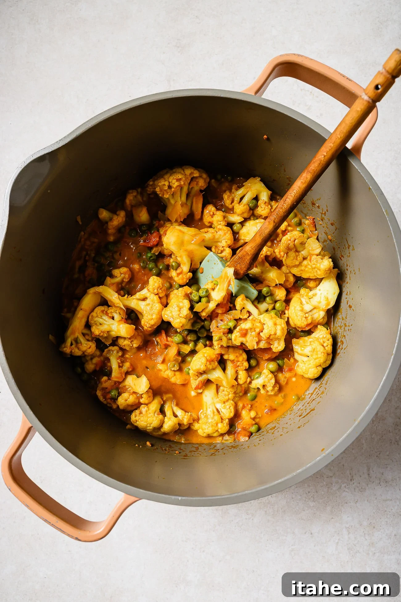 Cauliflower and peas in a pot with coconut curry sauce. 