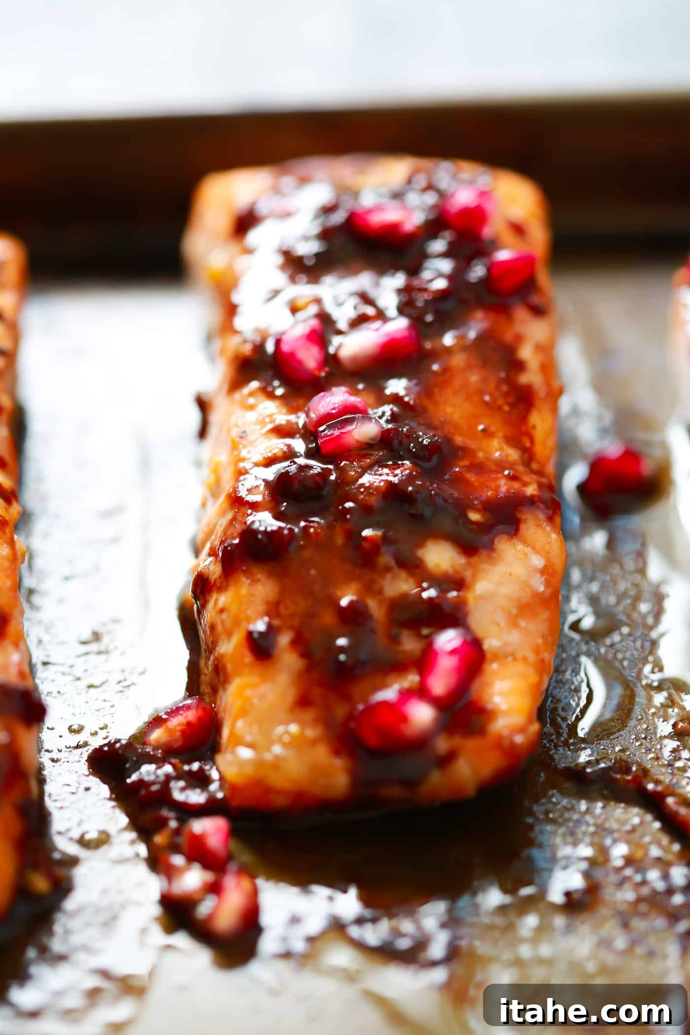 The easiest Pomegranate Glazed Salmon you will ever make. It only requires 4-ingredient and the glaze has no added sugar, but has a delicious tangy flavor! A stunning final presentation of pomegranate glazed salmon on a plate, garnished with fresh herbs and pomegranate seeds.