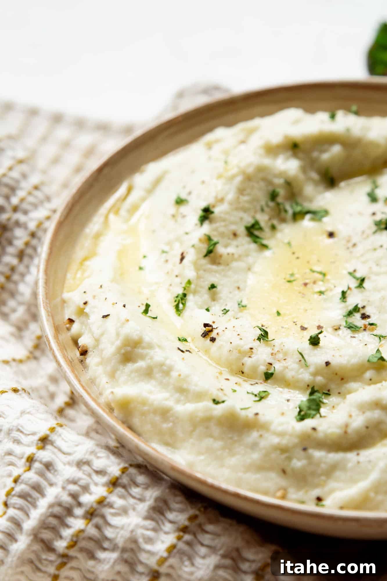 Close-up view of a beautifully garnished bowl of mashed cauliflower, ready to be served.