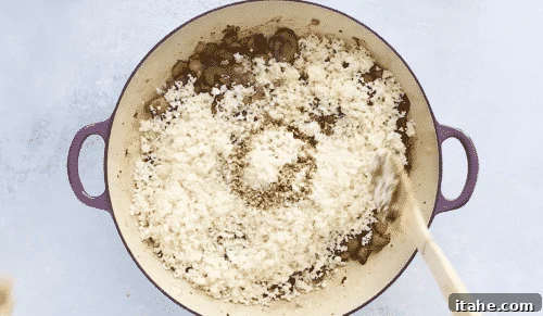 Low-Carb Cauliflower Rice 11 Cauliflower rice absorbing broth in a skillet