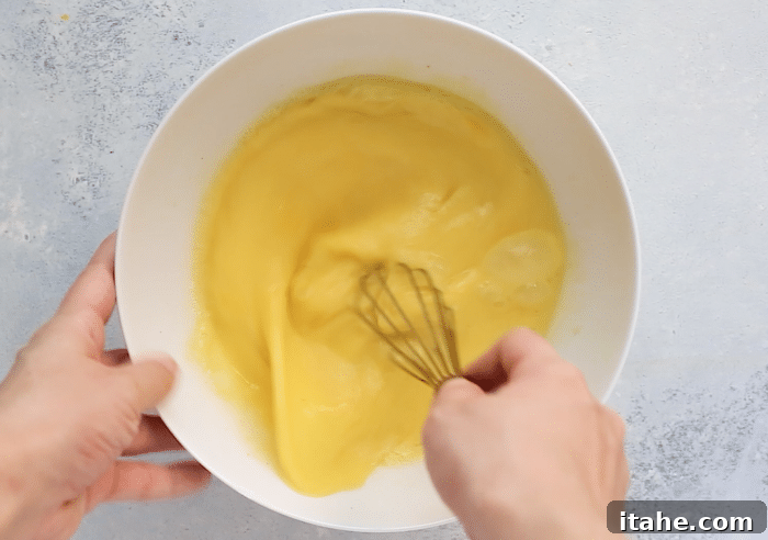Close-up of a bowl containing beaten eggs mixed with milk and seasonings, ready to be poured.