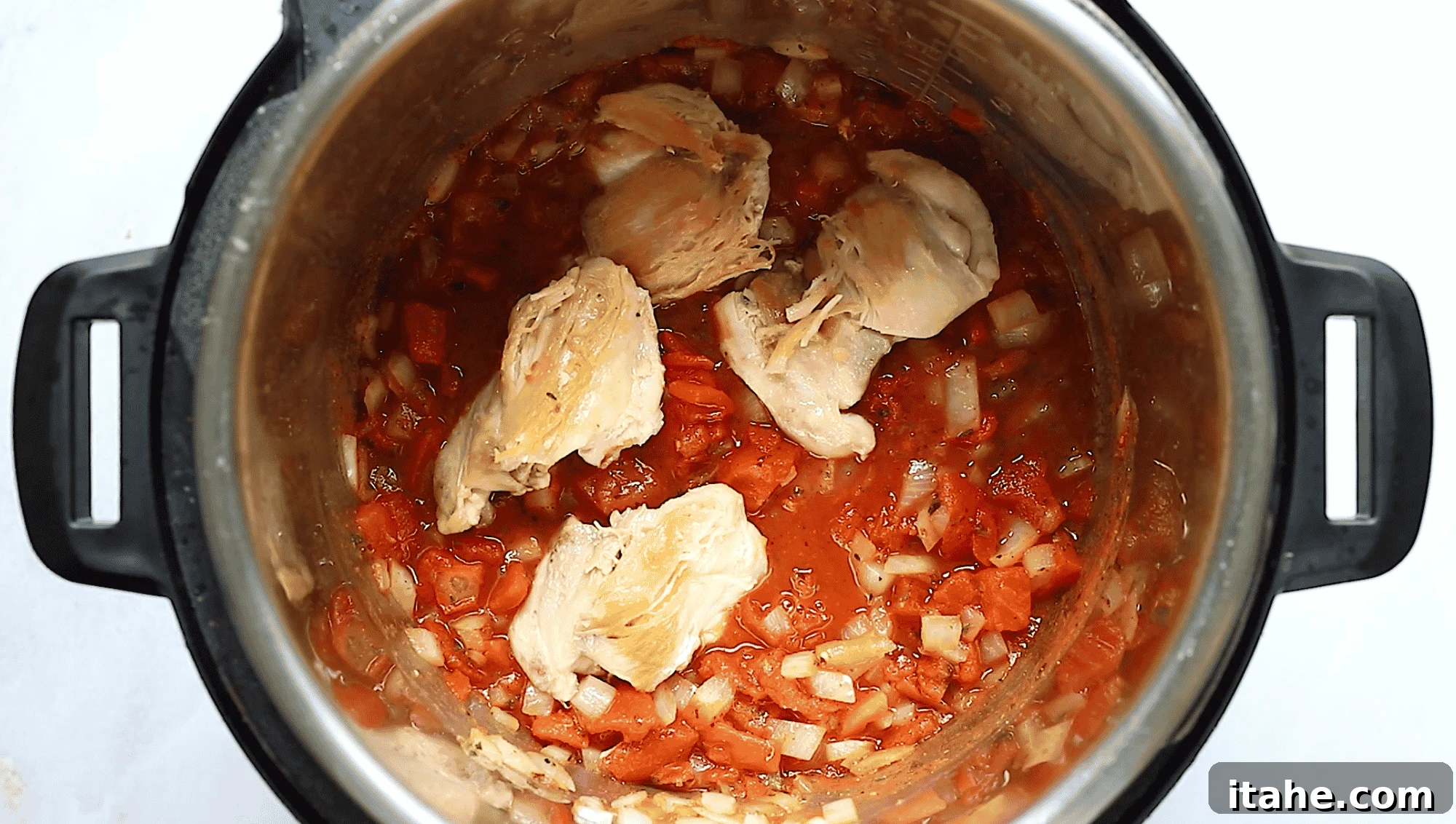 Quick Instant Pot Mediterranean Chicken 5 Overhead view of Instant Pot bowl containing chicken thighs and tomato sauce.