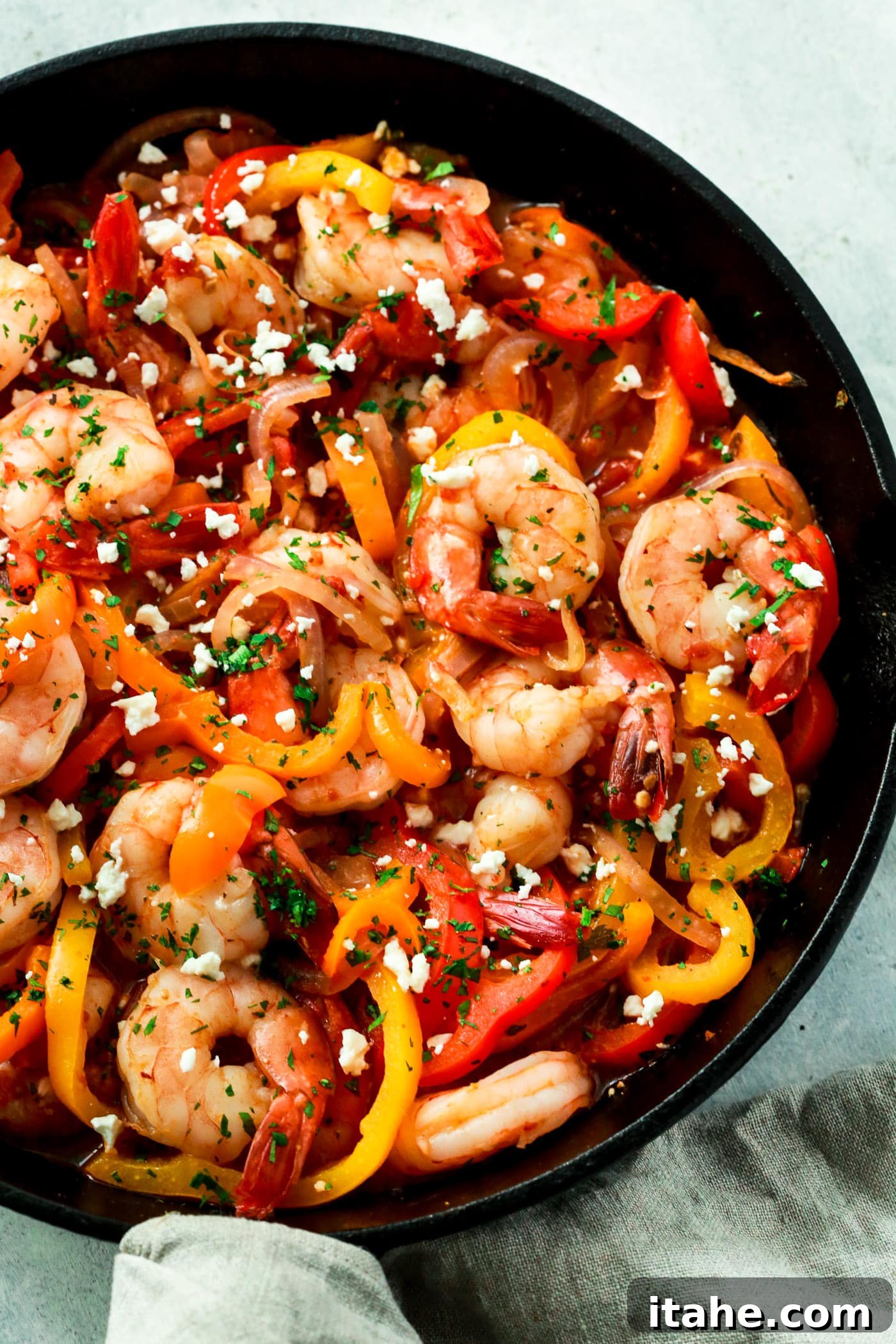 close up of a cast iron skillet with perfectly cooked shrimp, bell pepper, and onions. 