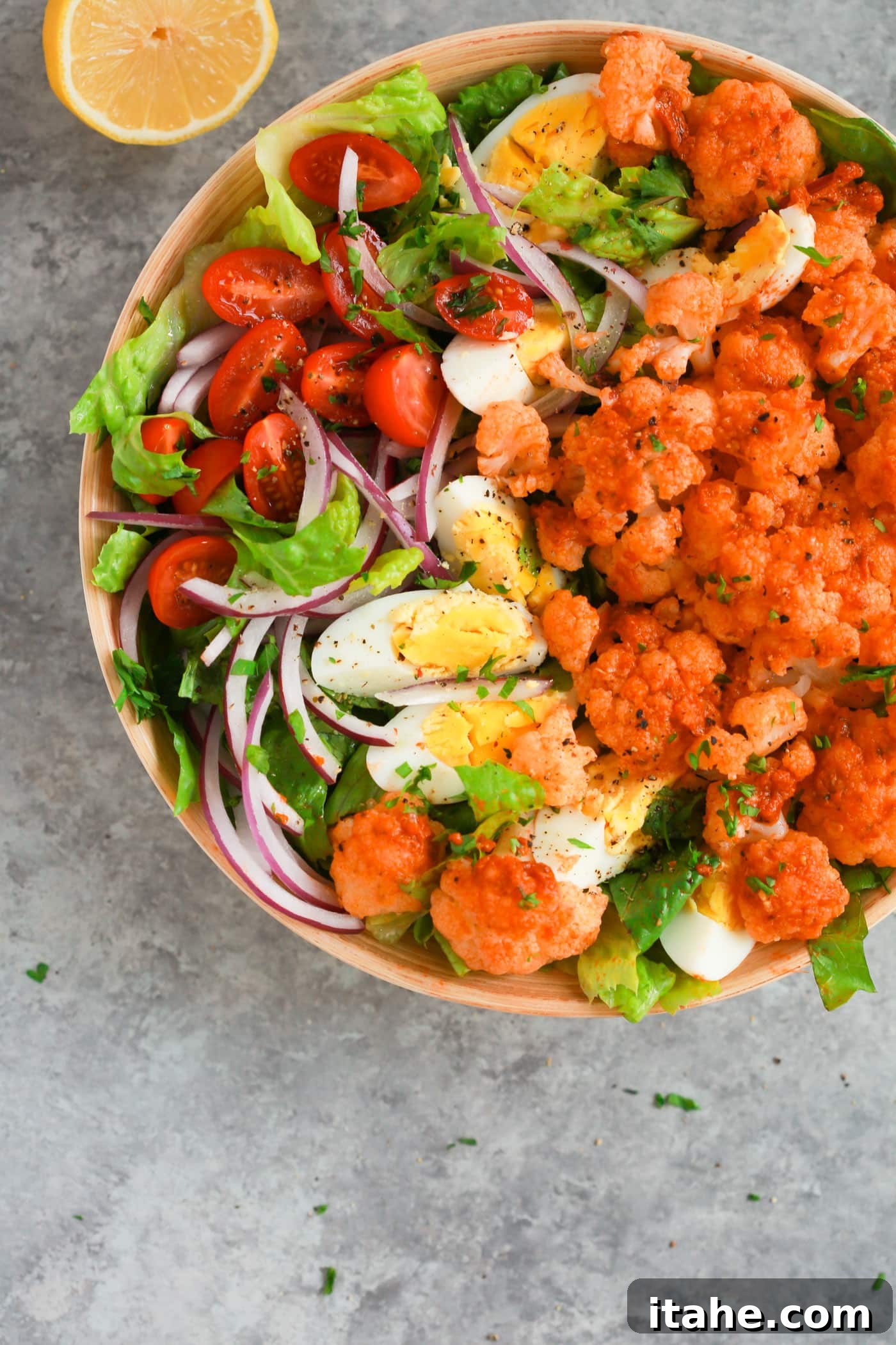 Fresh & Filling Low-Carb Lunches 11 Overhead view of a colorful Sun-dried Tomato Pesto Cauliflower Salad in a wooden bowl.