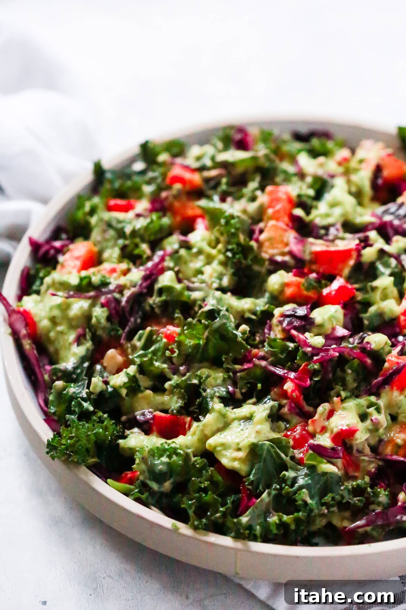 Fresh & Filling Low-Carb Lunches 13 Close-up view of a vibrant Simple Kale Salad with a creamy avocado dressing on a grey plate.