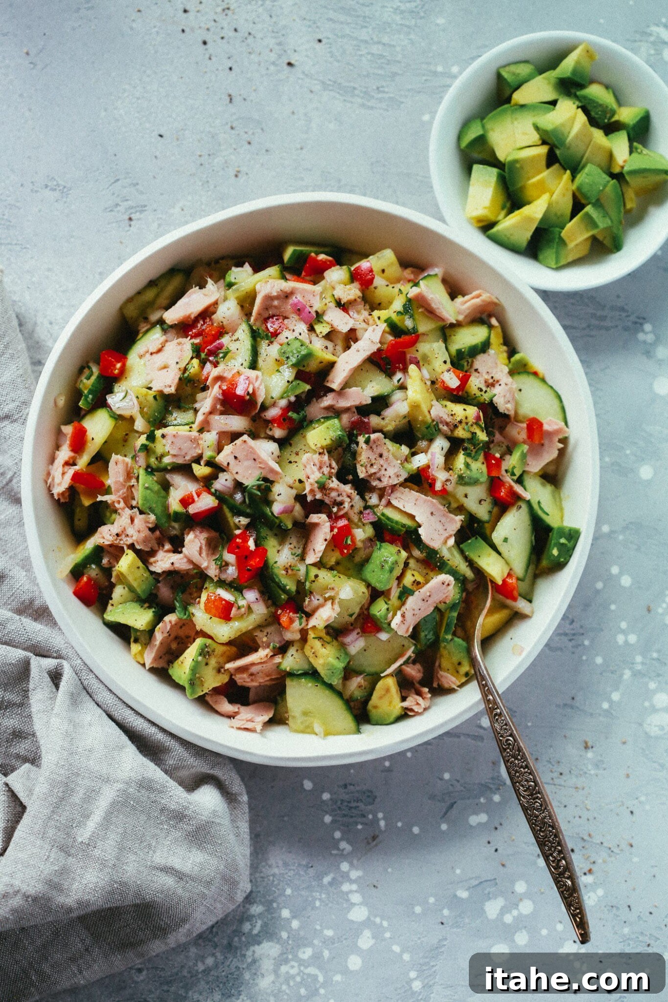 Fresh & Filling Low-Carb Lunches 14 Overhead view of a white serving bowl filled with Super Easy Avocado Cucumber Tuna Salad, ready to enjoy.