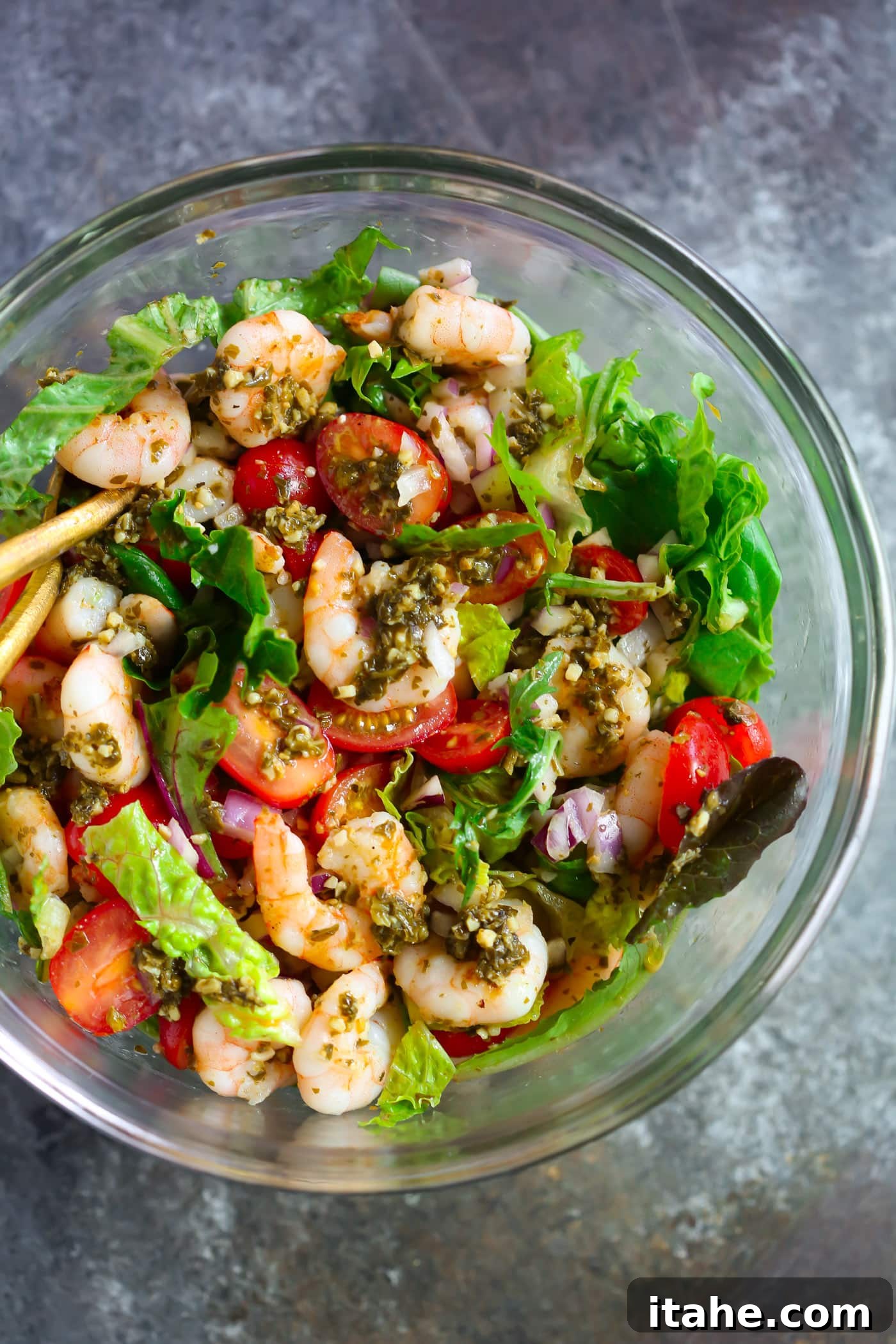 Fresh & Filling Low-Carb Lunches 9 Glass bowl containing a vibrant Pesto Shrimp Tomato Salad, with fresh ingredients visible.
