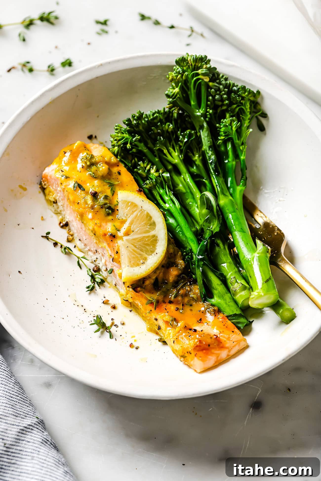 Maple mustard salmon on a white plate with broccolini. 