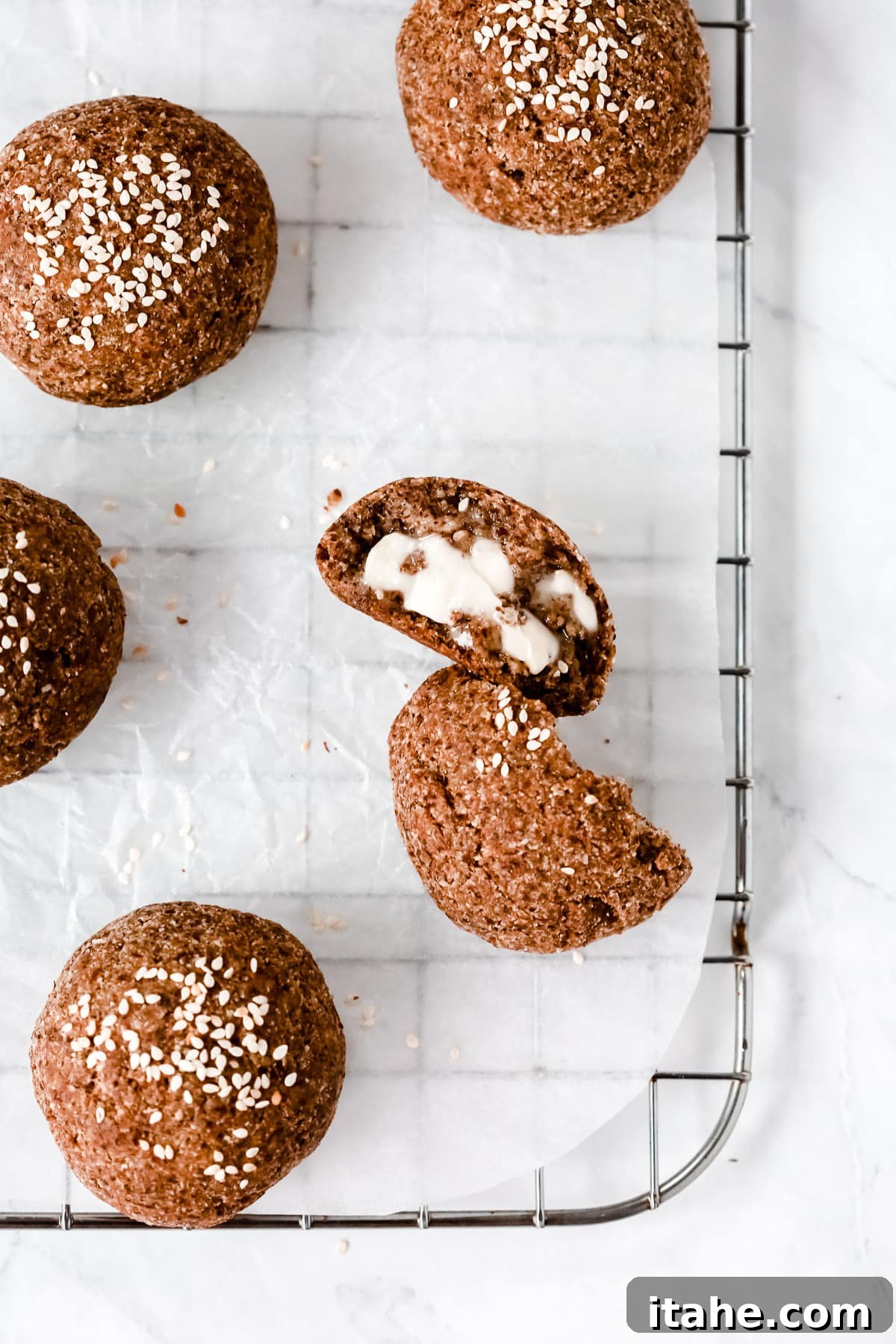 Overhead photo of a dinner roll cut opened on a cooling rack.