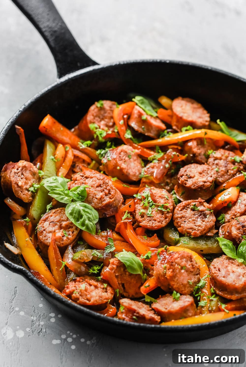 Italian Sausage, Onions and Peppers Skillet in a close-up shot, garnished with fresh basil