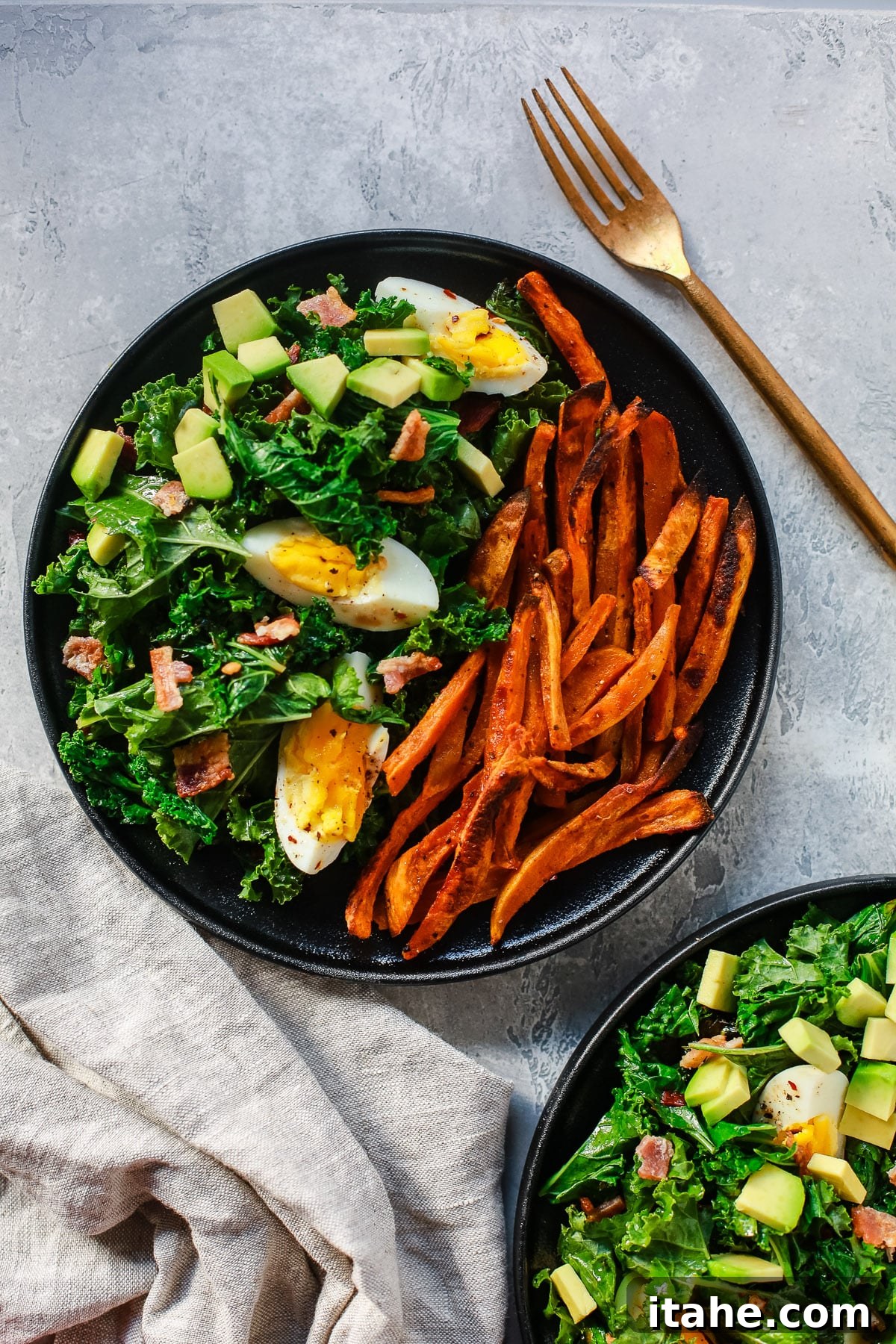 Close-up of a colorful kale salad with sweet potato, egg, bacon, and avocado.