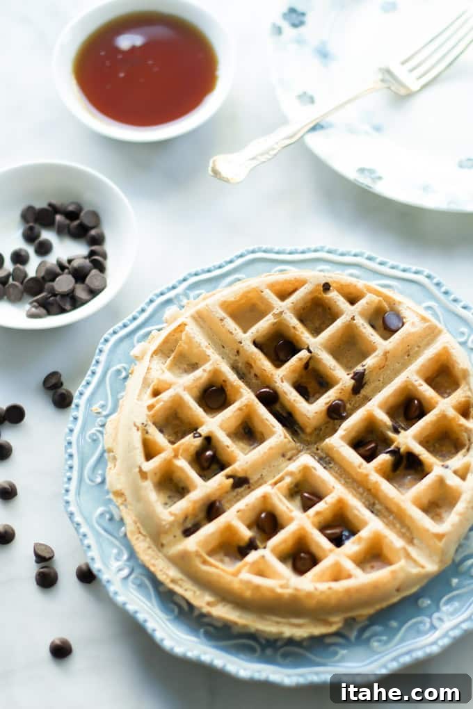 A serving of almond butter waffle on a blue plate, garnished with fresh berries and maple syrup.