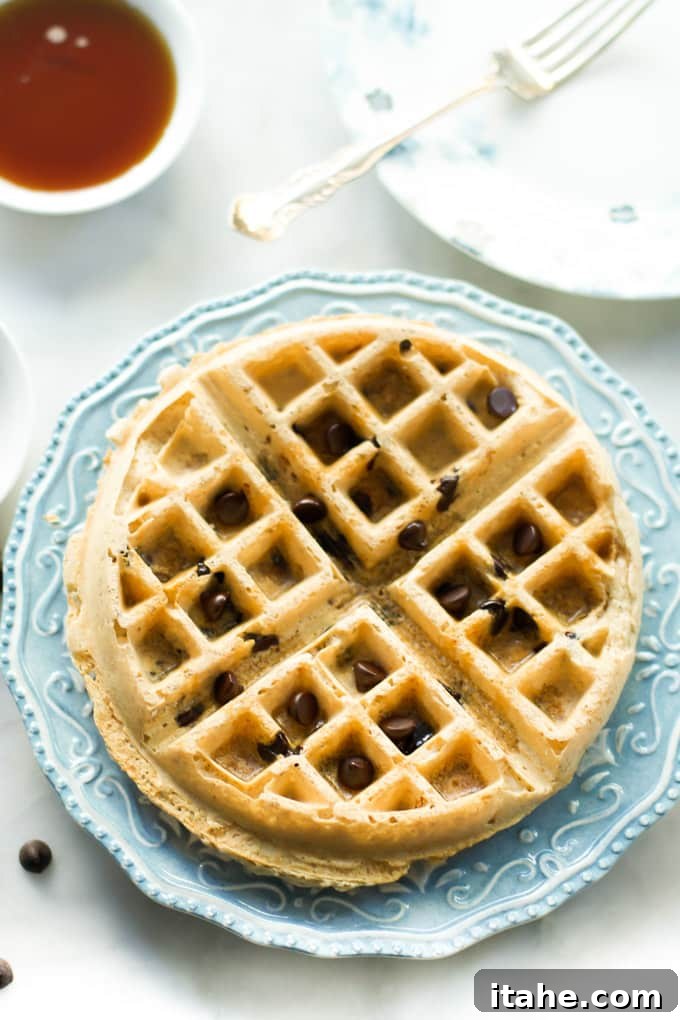 A single almond butter waffle, perfectly cooked and golden brown, on a white plate.