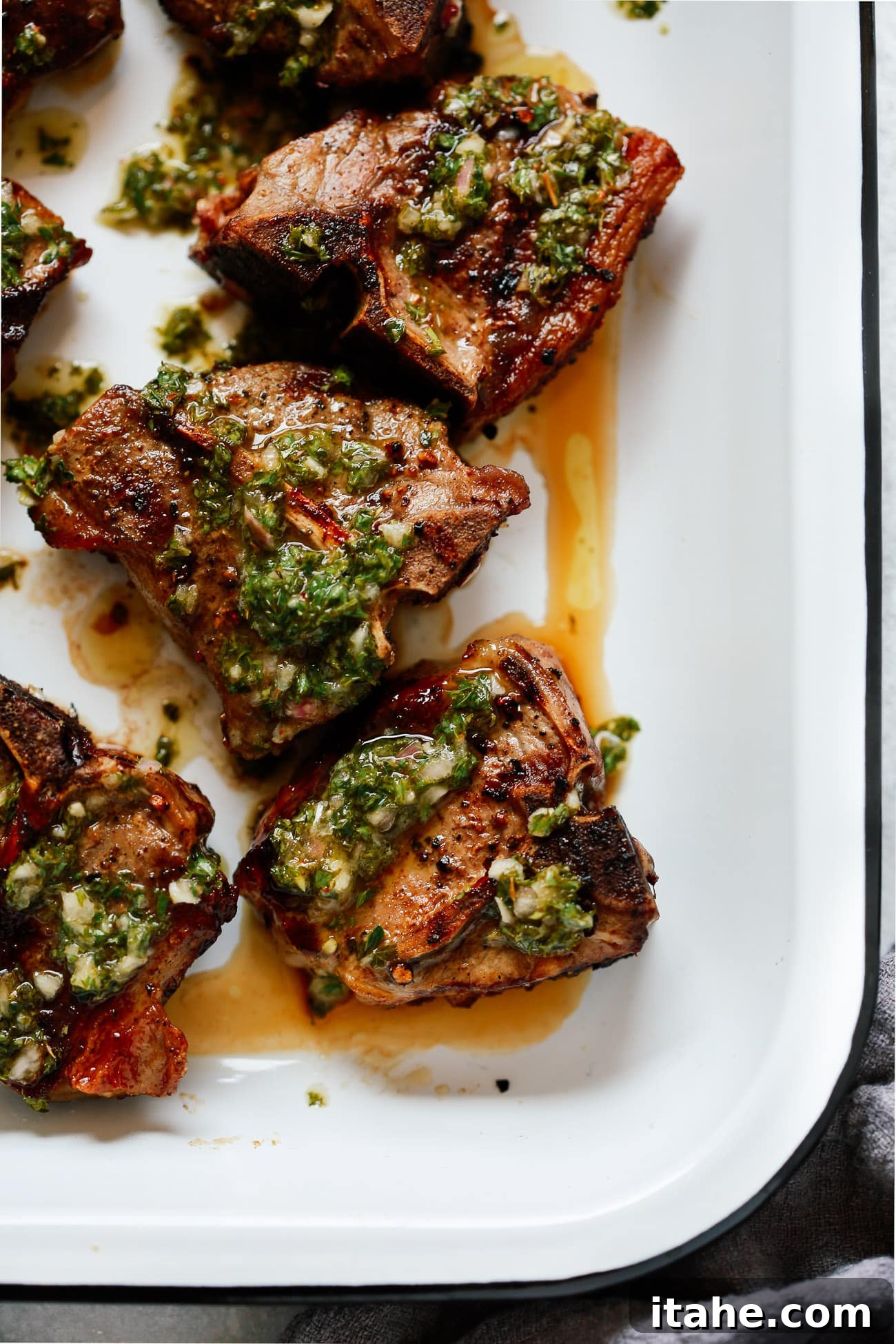 Marinated lamb chops soaking in a flavorful chimichurri sauce, ready for grilling.