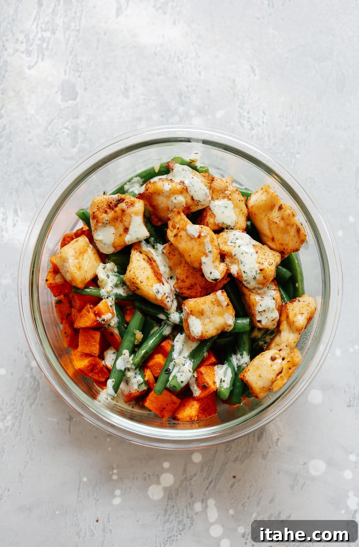 meal prep dinner of chicken and vegetables in pesto sauce in a glass bowl 