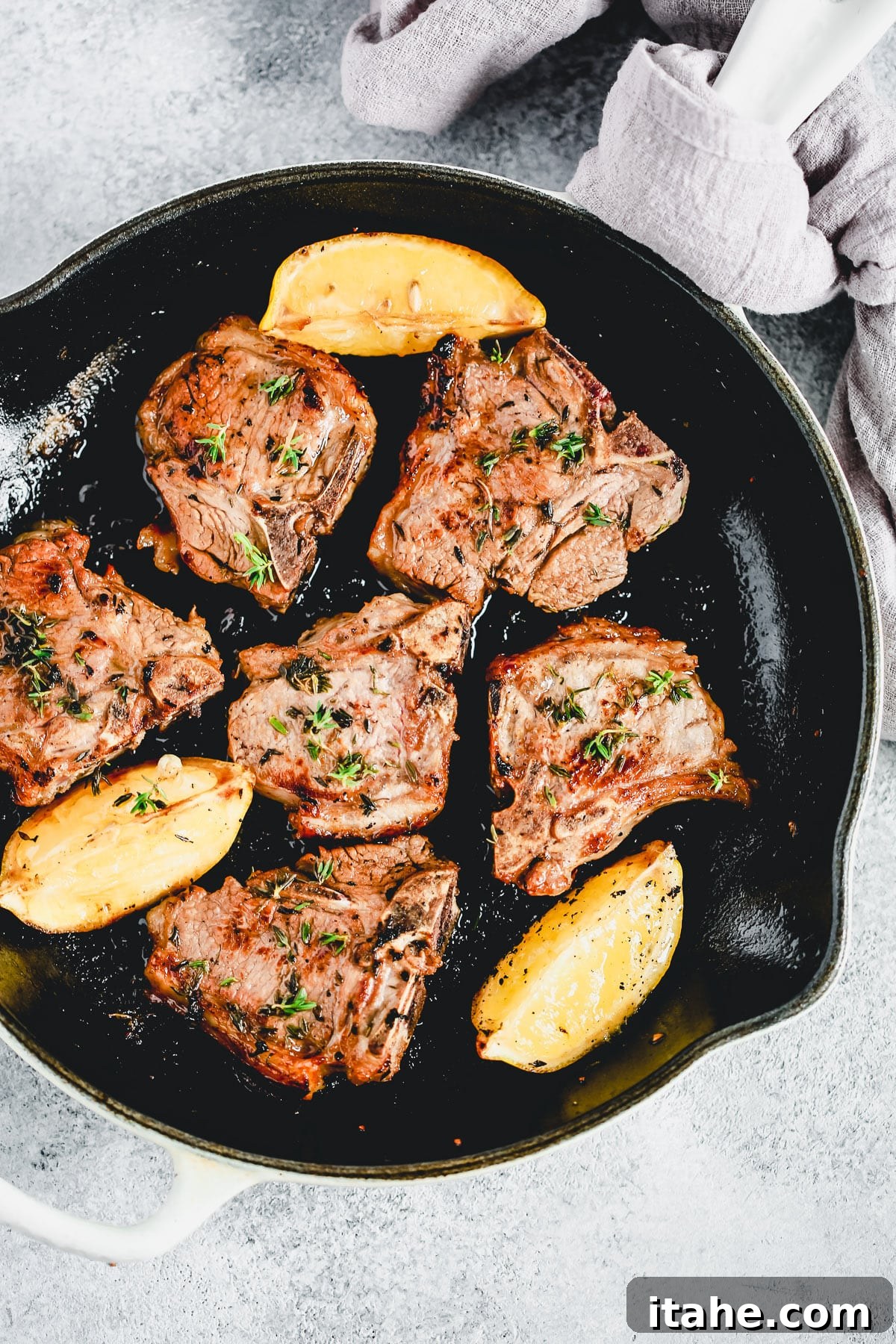 Cooking lamb chops in a cast iron skillet with garlic and herbs