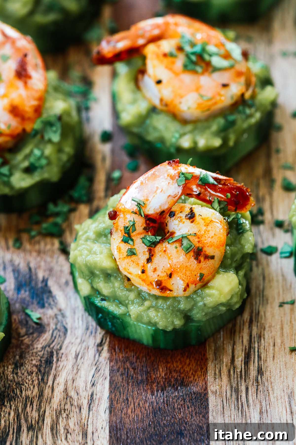 Slices of cucumber topped with guacamole and shrimp