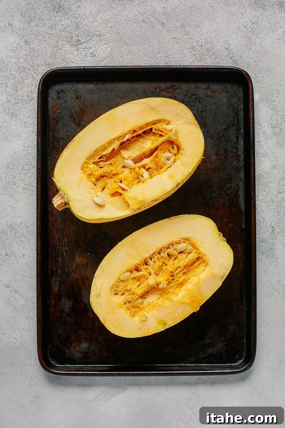 Spaghetti squash cut in half, revealing the vibrant yellow flesh and seeds.