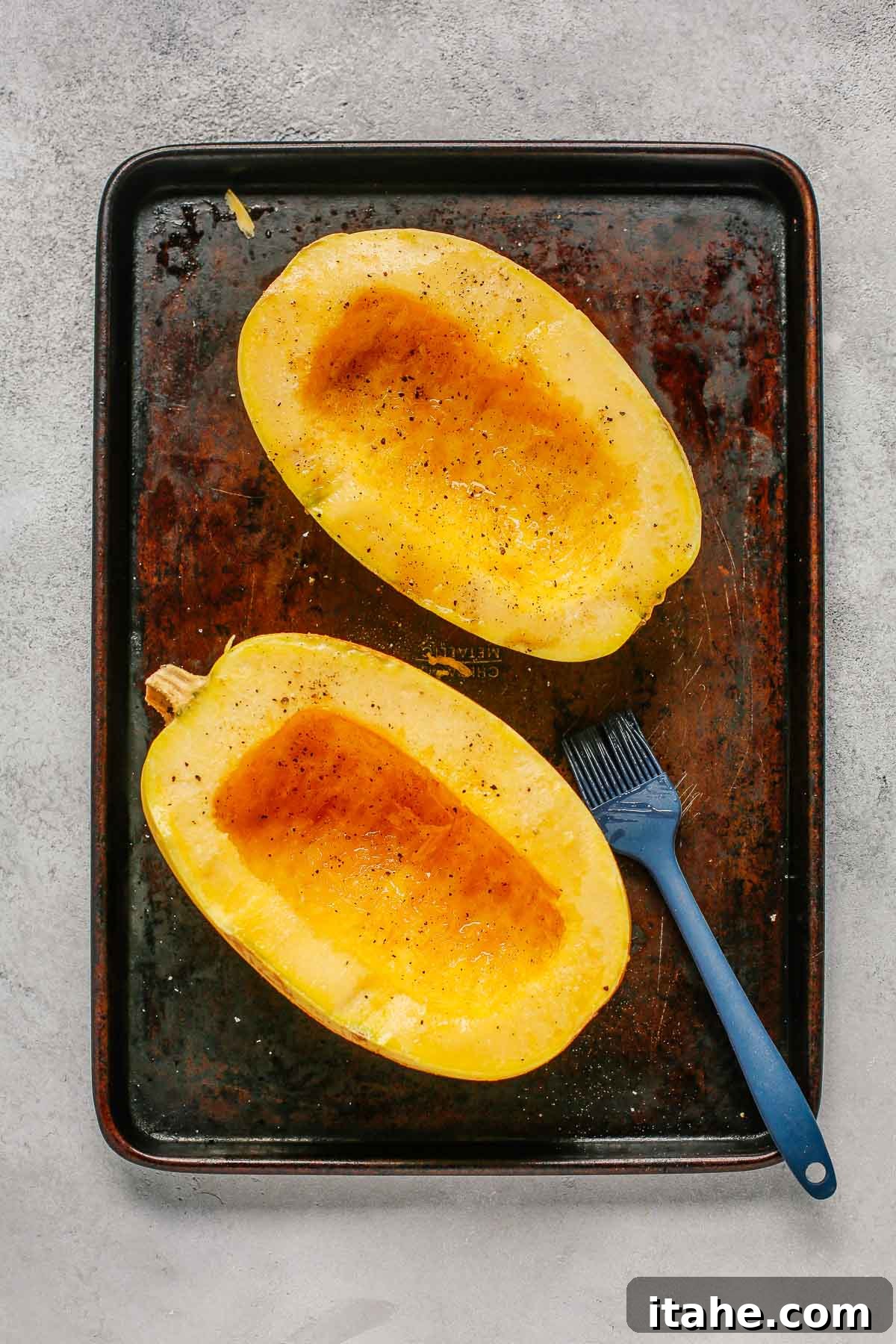 Spaghetti squash halves seasoned with olive oil, salt, and pepper, ready for the oven.