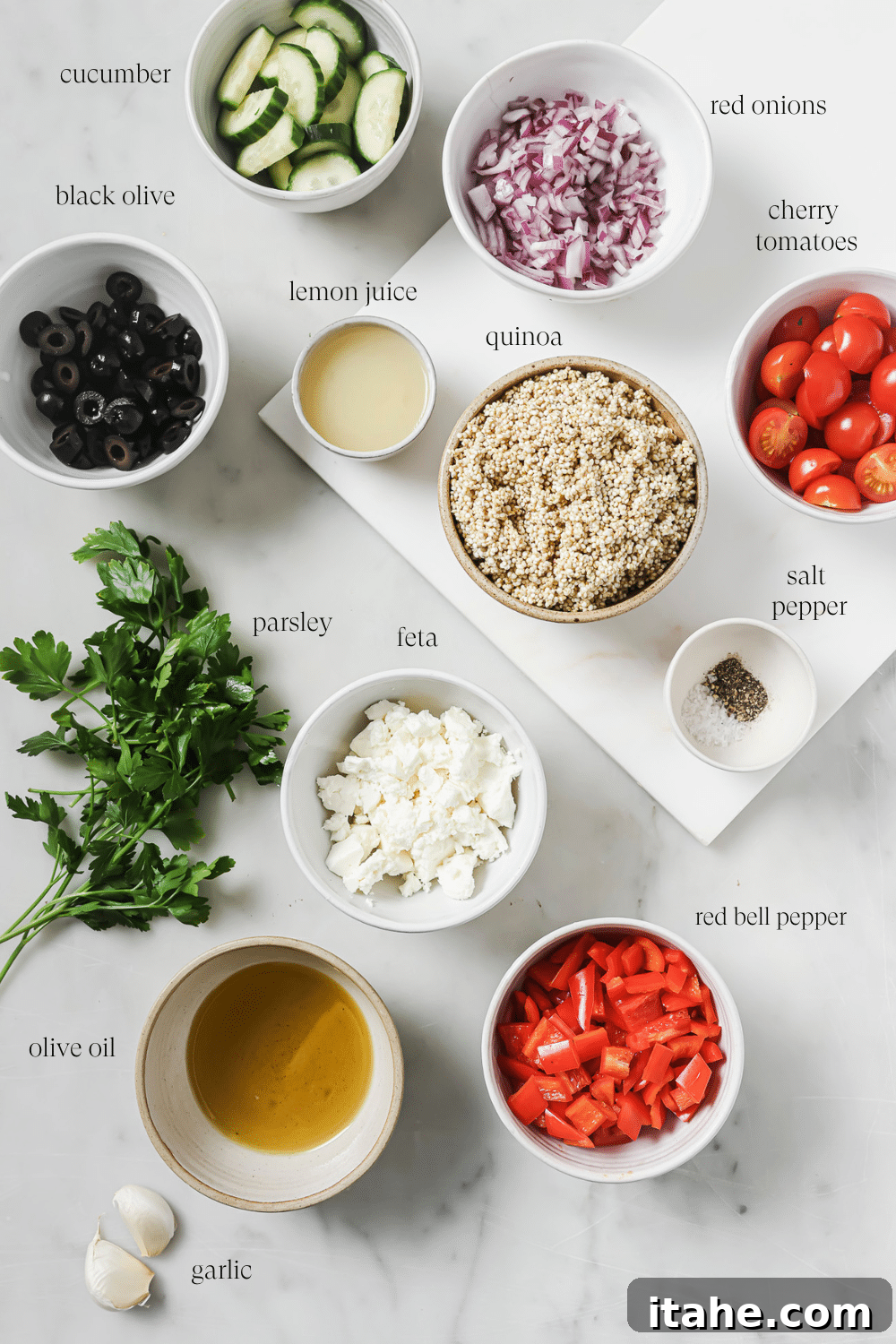 Pre-measured ingredients for Greek quinoa salad and dressing in small bowls on a white background.
