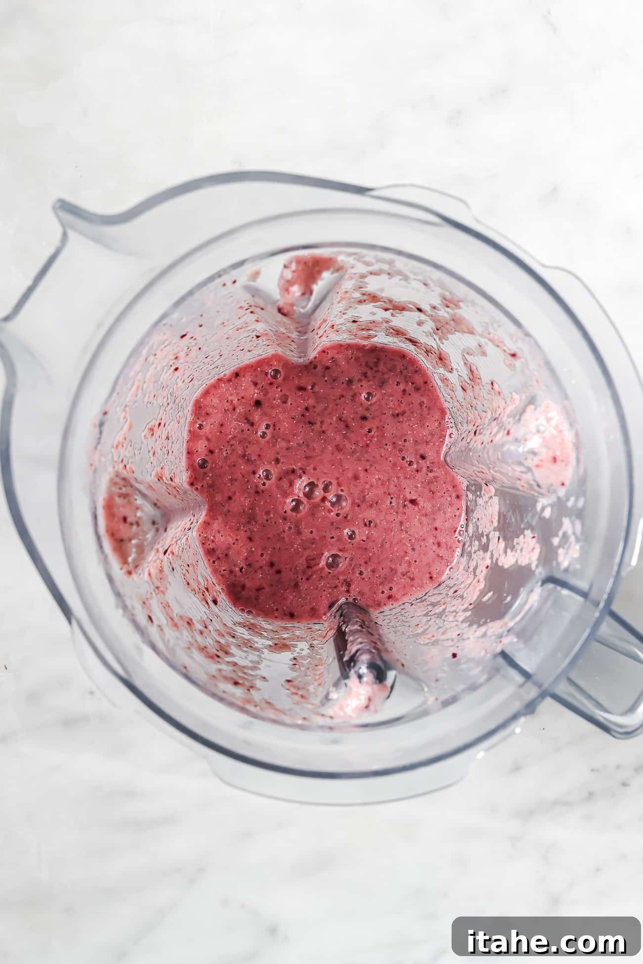 Overhead view of a cherry smoothie in a blender. 