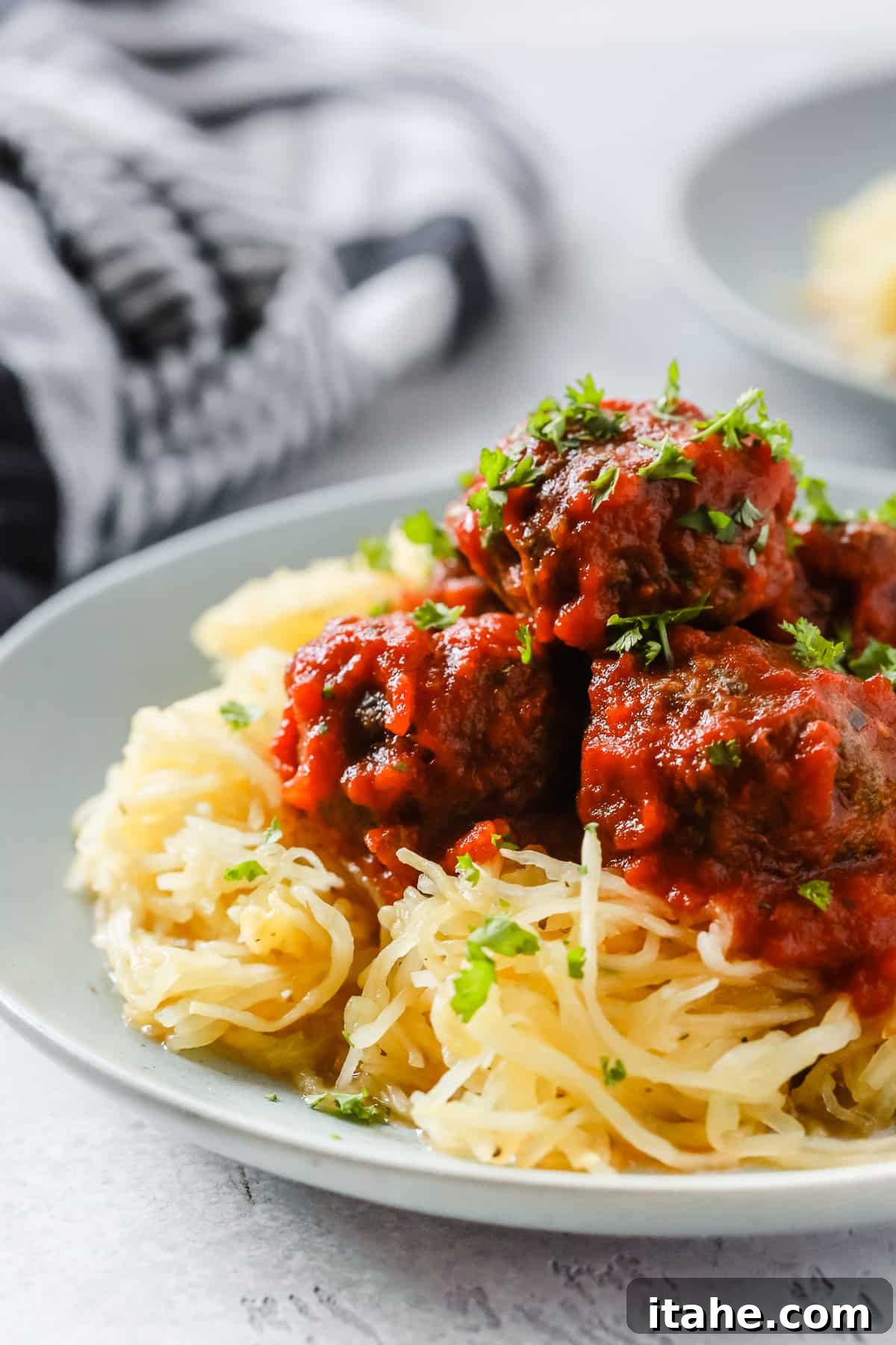 Effortless Keto Dinners 3 Close-up of spaghetti squash intertwined with savory meatballs and rich sauce.