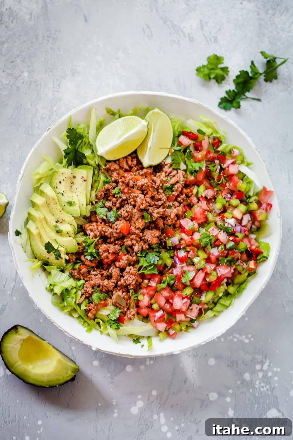 Effortless Keto Dinners 4 Overhead view of a vibrant taco salad in a pristine white bowl, showcasing its fresh ingredients.