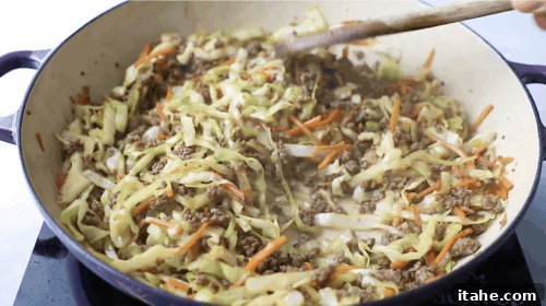 Unwrapped Egg Roll Bowl 10 Cooking ground beef in a skillet with a wooden spoon as the first step for making Egg Roll in a Bowl.