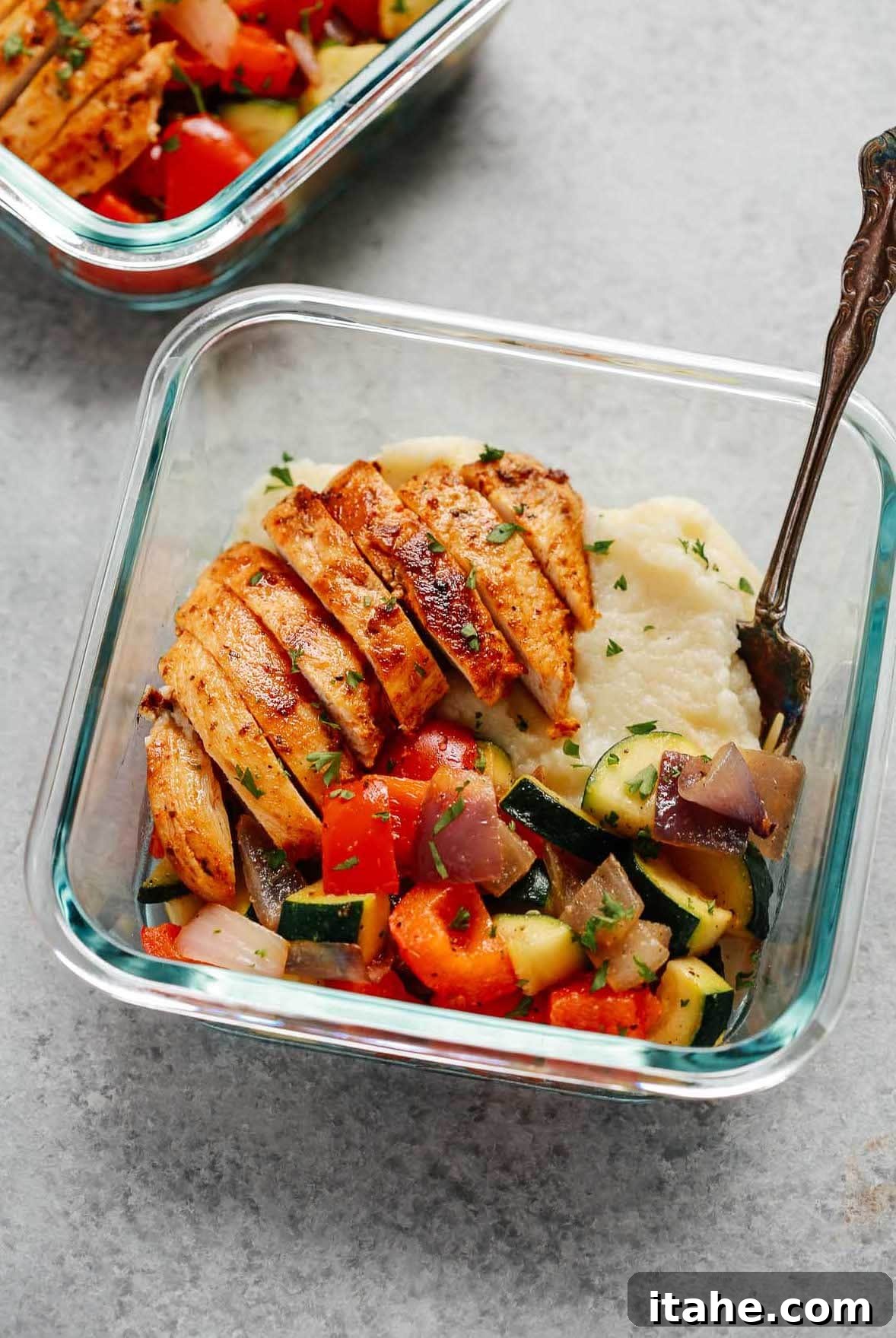 sliced baked chicken breast, cooked mixed vegetables and cauliflower mashed potatoes in square glass meal prep container