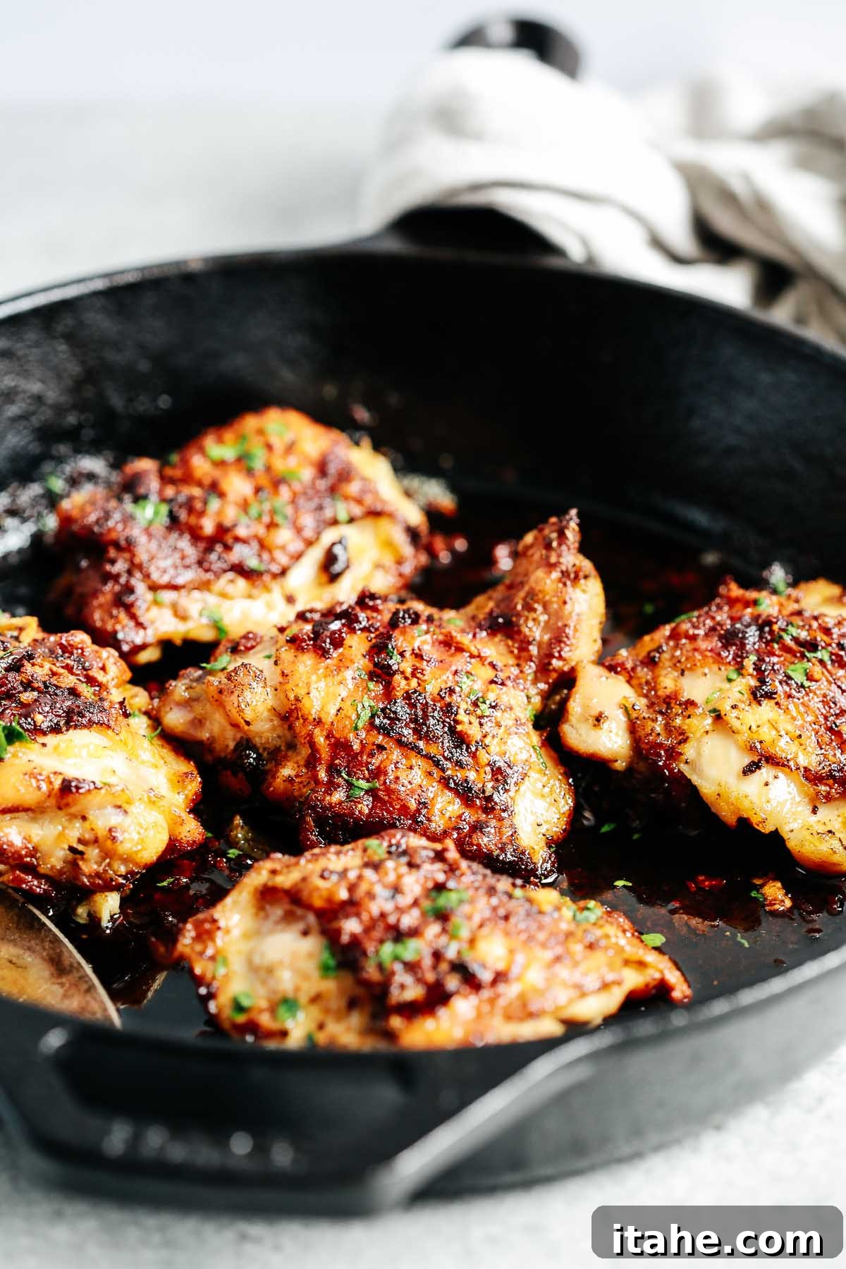 Closeup view of cooked chicken thighs in a skillet with butter sauce