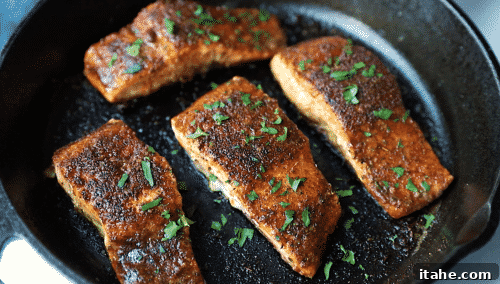 An overhead view of a cast iron skillet containing freshly cooked blackened salmon.