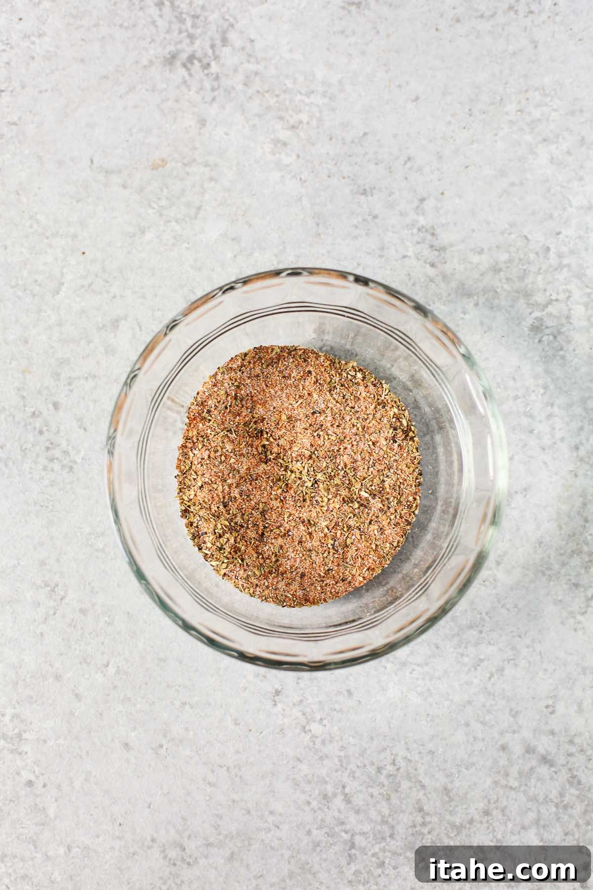 A small glass prep bowl filled with a homemade blackening spice blend, showcasing the rich colors and textures of the spices.