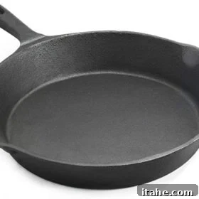 A closeup image showing the well-seasoned, dark surface of a cast iron skillet, ready for cooking.